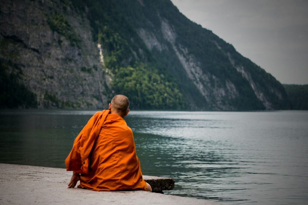 monk sitting near ocean
